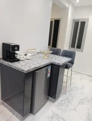 a kitchen with a granite counter top and chairs at Bright Apartment, 10 minutes from Gueliz and 7 minutes from Majorelle Garden in Marrakech
