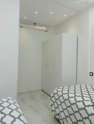 a white bedroom with a bed and a white wall at Bright Apartment, 10 minutes from Gueliz and 7 minutes from Majorelle Garden in Marrakech