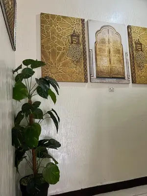 a plant in a pot next to a wall with paintings at Stylish 2-Bedroom City Apartment in the city of Marrakech in Marrakech