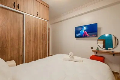 a bedroom with a white bed and a tv on the wall at Central Luxury Gem marrakech 3BR in Marrakech