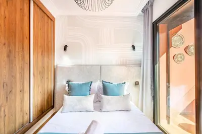 a bedroom with a white bed with blue pillows at Appartement Élégant Quartier Hivernage in Marrakech