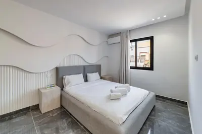 a bedroom with a bed with white sheets and a window at Appartement 3 Chambres Luxe au Cœur de Guéliz in Marrakech