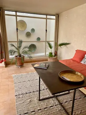 a living room with a table and a large window at Dar Aji, votre maison d'architecte privatisée en médina in Marrakech