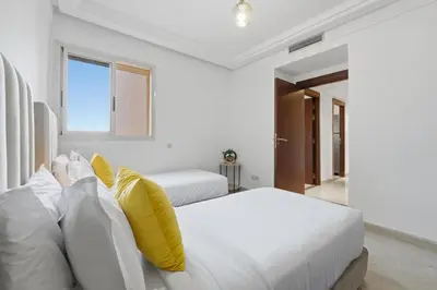 a white bedroom with two beds with yellow pillows at Modern apartment, swimming pool and sports in Marrakech
