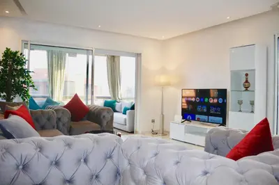 a living room with a white couch and a tv at Red nelbrj appartement in Marrakech