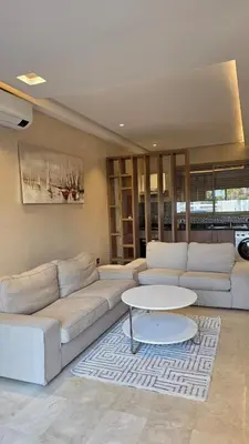 a living room with a white couch and a table at Spacious Ground Floor Oasis with Pool & Golf Course View 1rom in Marrakech