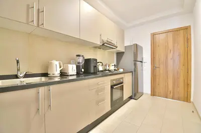 a kitchen with white cabinets and a wooden door at Noria Residence - Premium 2BR Apartment with Pool View in Marrakech