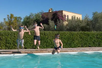 three young boys jumping into a swimming pool at Fawakay Villas in Sfiani