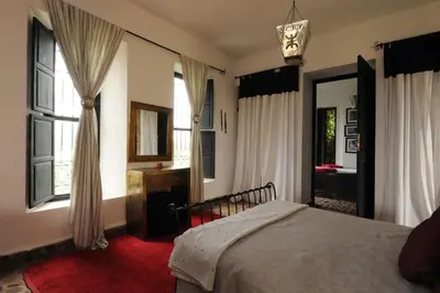 a bedroom with a bed and windows and a mirror at Fawakay Villas in Sfiani