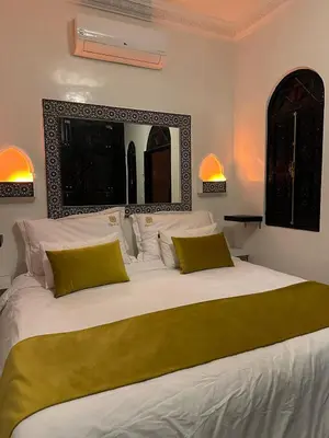 a large bed with white sheets and yellow pillows at Ryad Lalla khadija in Marrakech