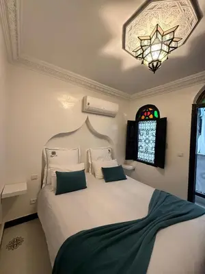 a bedroom with a large white bed with a chandelier at Ryad Lalla khadija in Marrakech