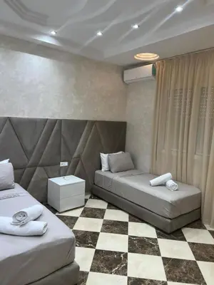 a bedroom with two beds and a checkered floor at Appartement Abdessamad Hébergement réservé aux familles in El Gouassem