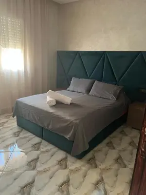 a bed with a blue headboard in a bedroom at Appartement Abdessamad Hébergement réservé aux familles in El Gouassem