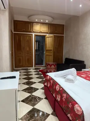 a room with a bed and a checkered floor at Appartement Abdessamad Hébergement réservé aux familles in El Gouassem