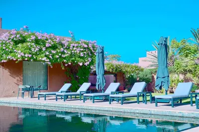 a group of chairs and umbrellas next to a swimming pool at Royal Palm Luxury Villa Heated Pool Spa in Moussiha