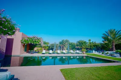 a swimming pool in a resort with chairs and palm trees at Royal Palm Luxury Villa Heated Pool Spa in Moussiha