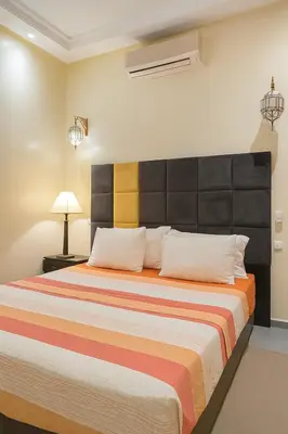 a bedroom with a large bed with a large headboard at Cycas family apart ground floor parking in Marrakech