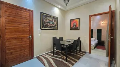 a dining room with a table and chairs and a door at Cycas Family Apart grand wifi parking in Marrakech