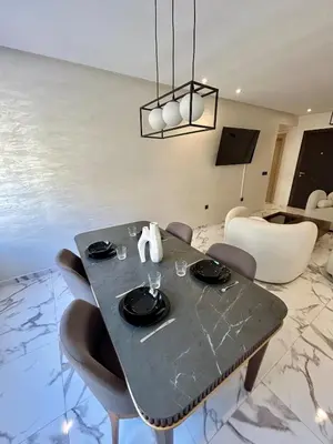 a dining table and chairs in a living room at Palmeraie Gates 2 chambres Piscine et Parking in Marrakech