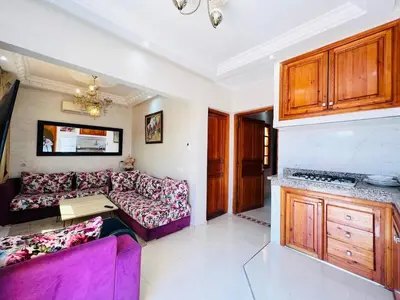 a living room with a purple couch and a kitchen at Cycas Family aparts 1 ch salon parking in Marrakech