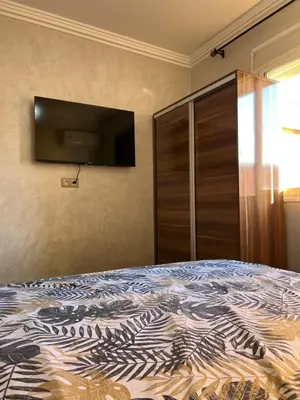 a bedroom with a bed and a flat screen tv at Appartement bien équipé avec piscine sur Marrakech in Marrakech