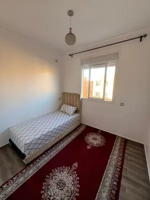 a bedroom with a bed and a window and a red rug at Appartement bien équipé avec piscine sur Marrakech in Marrakech