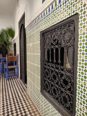 a black gate on the side of a tiled wall at Riad Sijane in Marrakech