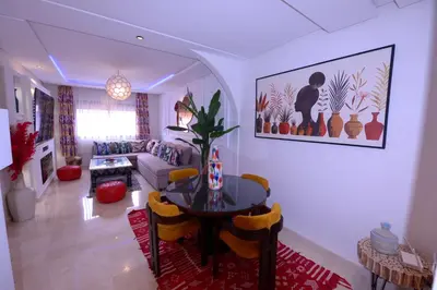 a living room with a table and a couch at Appartement Spacieux Idéal Séjours Longs in Marrakech