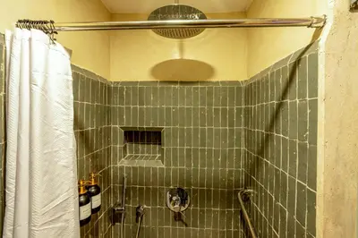 a green tiled shower with a shower curtain in a bathroom at Riad Janate BAHIA & Spa in Marrakech