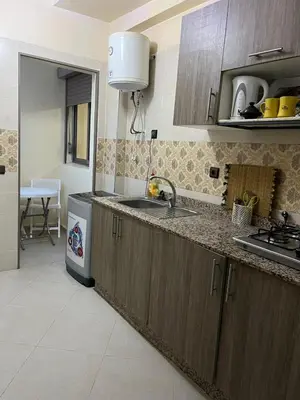 a kitchen with wooden cabinets and a sink and a dishwasher at Appartement très bien meublé in Marrakech