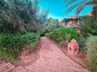 a brick path next to a house with a building at le pavillon de la palmeraie - Piscine et jardins in Marrakech