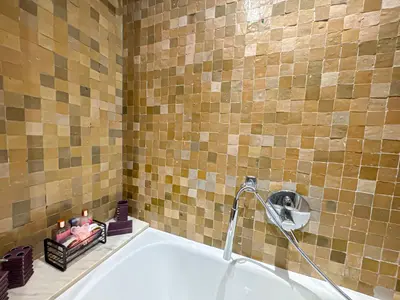 a bathroom with a tub and a tiled wall at le pavillon de la palmeraie - Piscine et jardins in Marrakech