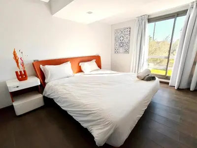 a bedroom with a bed with white sheets and a window at Duplexe Moderne 2 suites è Oliver Palm Resort in Marrakech