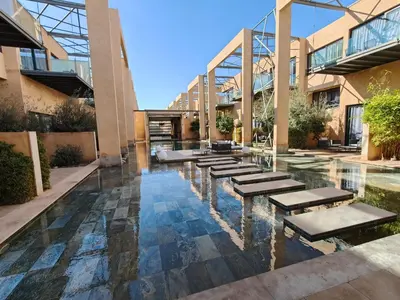 a pool in the middle of a building with benches at Duplexe Moderne 3 suites à Oliver Palm Resort in Marrakech