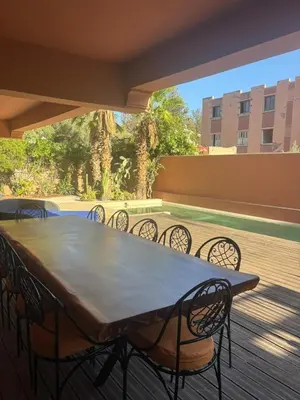 a table and chairs on a deck with a patio at Appartement centre Marrakech avec piscine in Marrakech