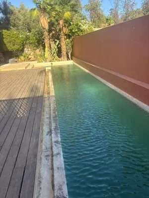a pool of water next to a wooden deck at Appartement centre Marrakech avec piscine in Marrakech