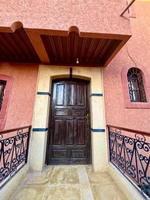 a wooden door on a pink building with a balcony at Appartement Kech in Marrakech
