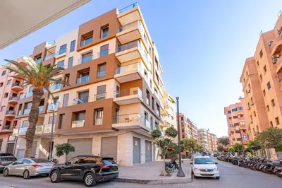 a tall building with cars parked in front of it at Appartement moderne en plein Gueliz in Marrakech