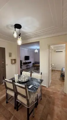 a dining room with a table and a living room at Appartement 2 chambres et 1 salon récemment rénové in Marrakech