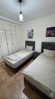two beds in a room with white walls at Appartement 2 chambres et 1 salon récemment rénové in Marrakech
