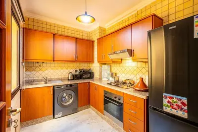 a kitchen with wooden cabinets and a washer and dryer at Perle Soft light and air conditioning in Marrakech