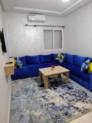a living room with a blue couch and a table at Mhamid Appartement 3 chambres in Marrakech