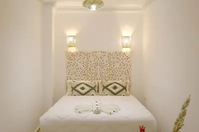 a small room with a white bed with two lights at Riad Armonia in Marrakech
