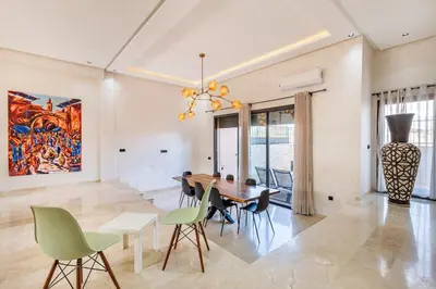 a dining room with a table and chairs and a painting at Villa Gina, Piscine, Terasse, 15 min du centre in Marrakech
