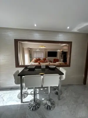 a dining room with a table and a living room at Spacieux duplex 3 chambres - Piscine et parking in Marrakech