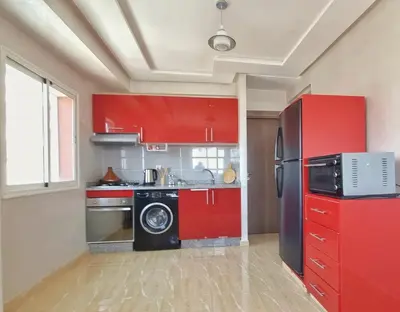 a kitchen with red cabinets and a refrigerator at Ilova 1 - Appartement Moderne au Centre de Marrakech in Marrakech