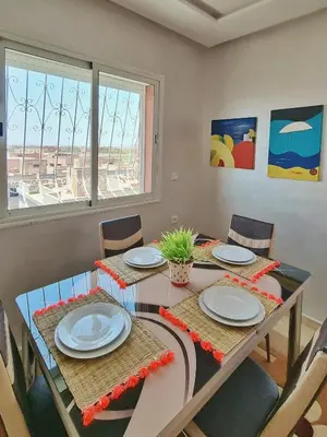 a dining room with a table with plates and chairs at Ilova 1 - Appartement Moderne au Centre de Marrakech in Marrakech