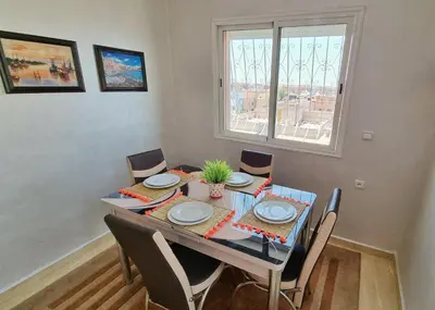 a dining room with a table and chairs and a window at Ilova 1 - Appartement Moderne au Centre de Marrakech in Marrakech