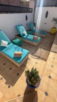 a patio with blue couches and a potted plant at Private - Riad Désiré Marrakech in Marrakech