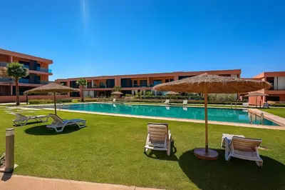 a pool with chairs and umbrellas next to a building at 2 chambres avec terrasse vue piscine in Marrakech